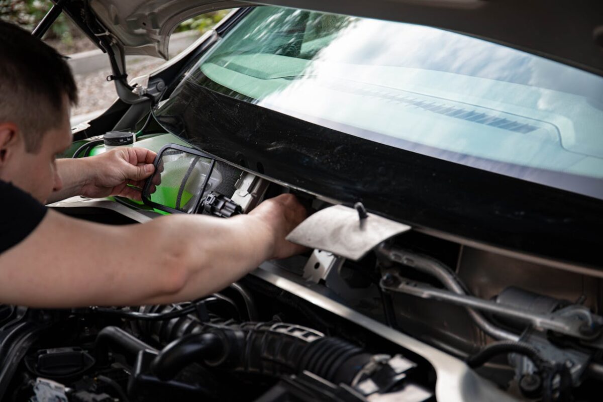 A mechanic working on car maintenance. Close-up of hands fixing vehicle engine.